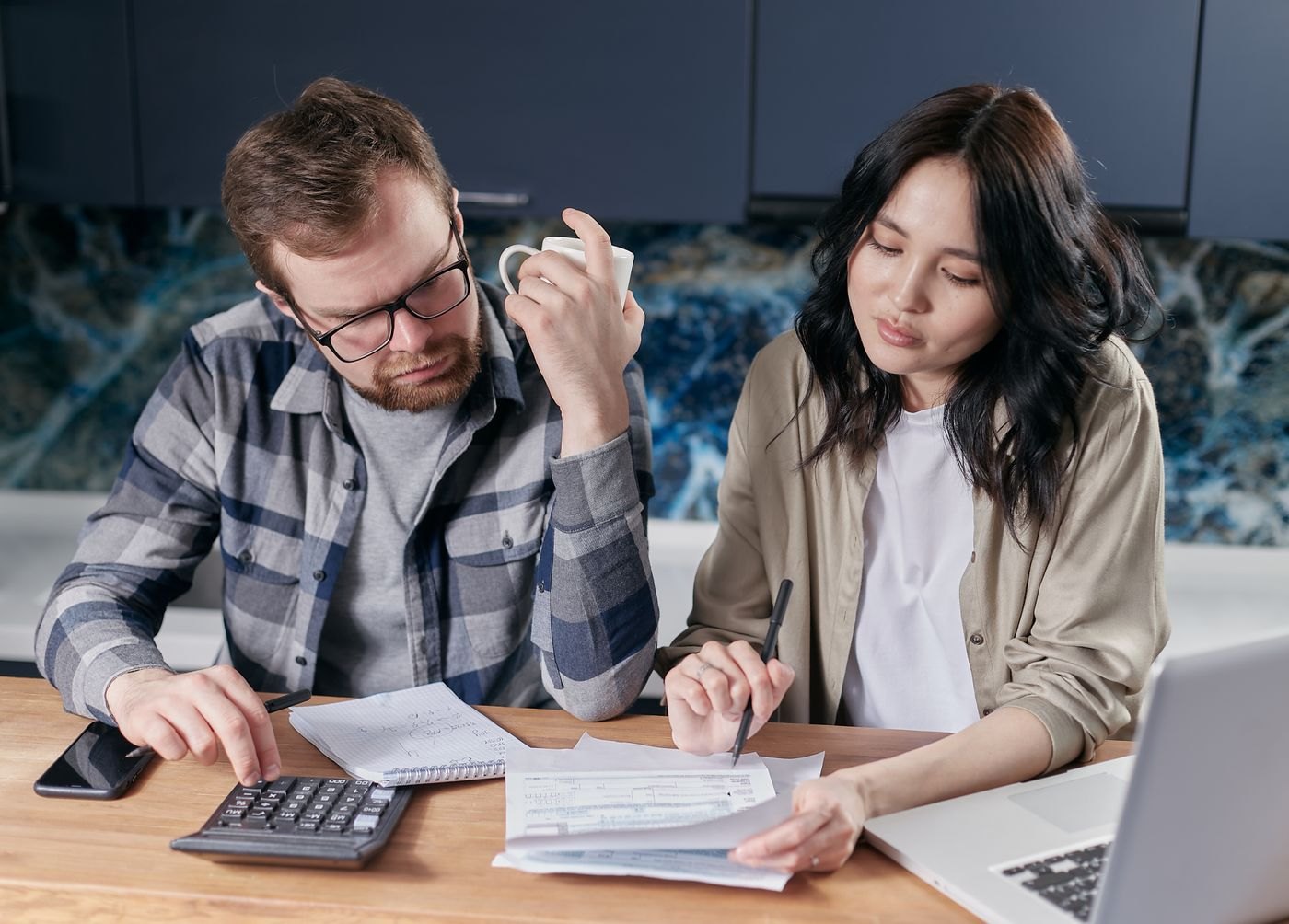 Two people reviewing household paperwork at a kitchen table
