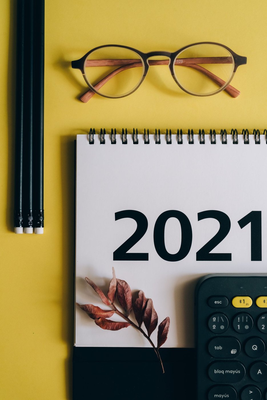 A desk calendar beside glasses and a calculator