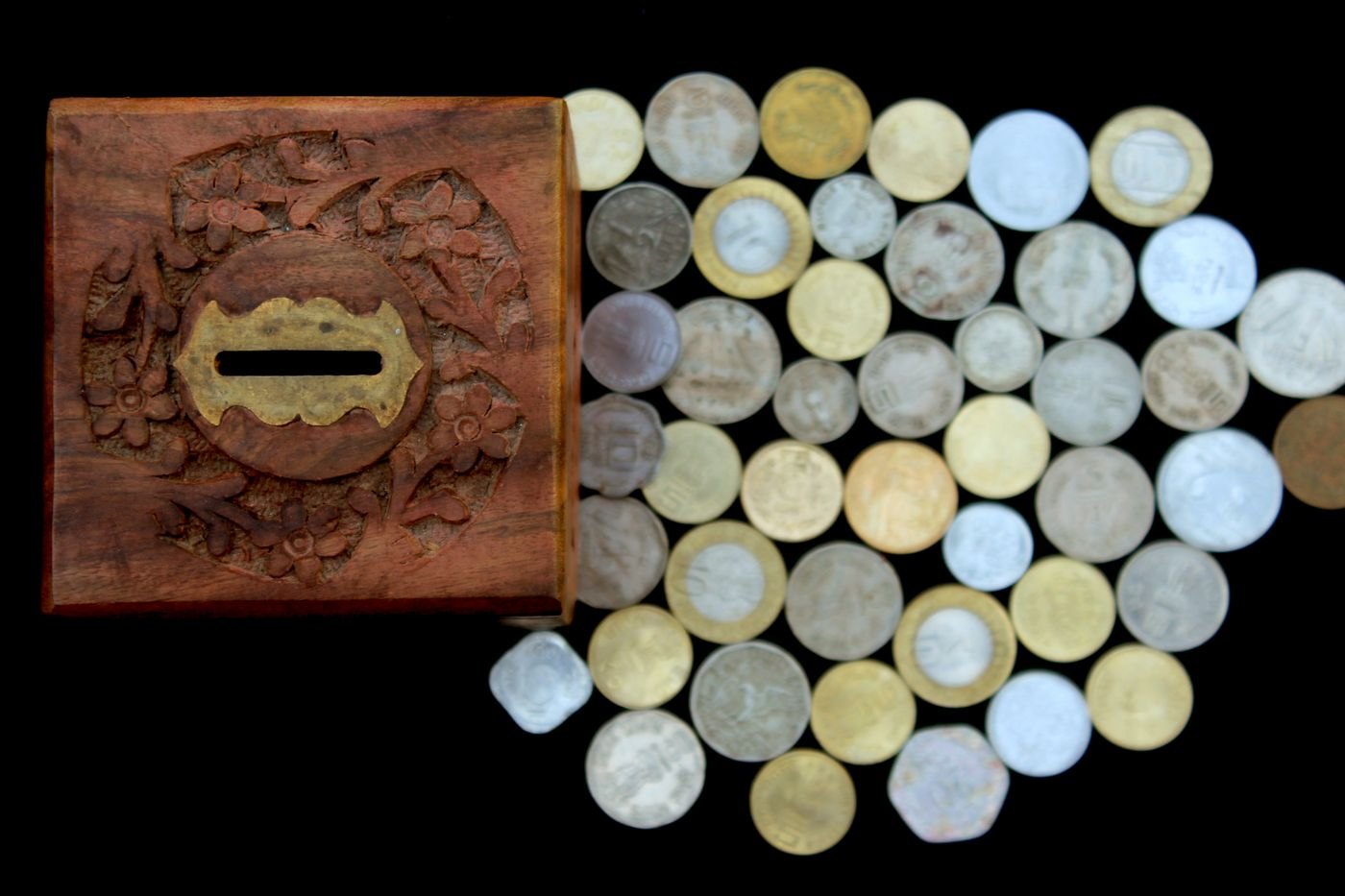 A savings box beside a collection of coins