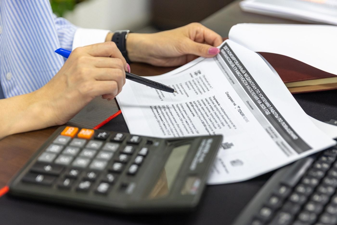 A calculator and handwritten review of financial documents