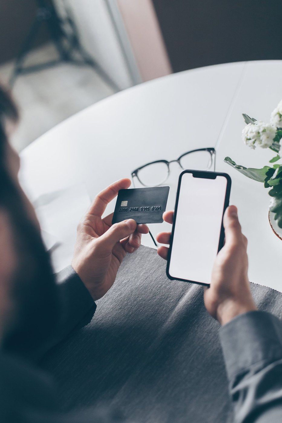 A person checking a phone beside a payment card